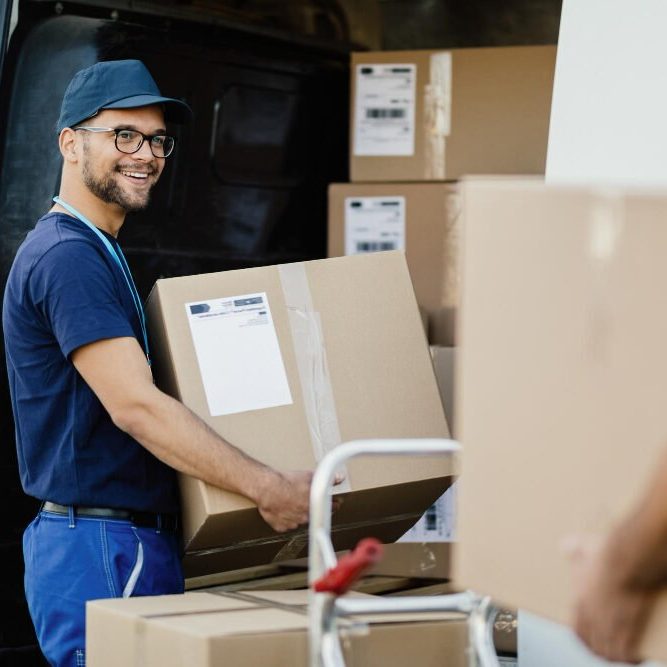 joven trabajador joven-trabajador-manual-feliz-que-lleva-cajas-carton-furgoneta-reparto-mientras-comunica-sus-colegas-